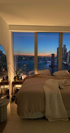 a bedroom with a large window overlooking the city at night, and a bed in front of it