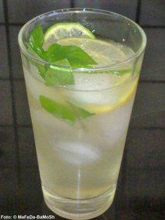 a tall glass filled with ice and lemon