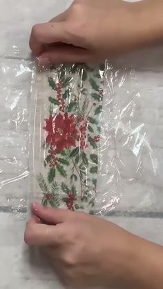 two hands holding plastic bags with red flowers on them