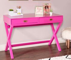 a pink desk with two pictures on the wall and a white rug in front of it