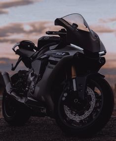 a black motorcycle parked on top of a dirt field