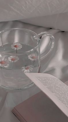 a glass cup filled with water next to an open book