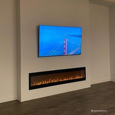 a flat screen tv mounted on the wall above a fireplace in a room with hardwood floors