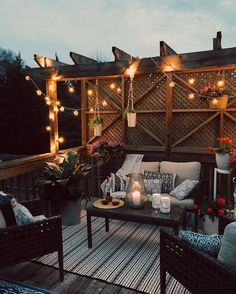 an outdoor deck with chairs and lights on it