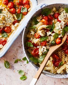 a bowl of pasta with tomatoes and spinach next to a casserole dish