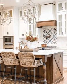 a kitchen with white cabinets and an island that has chairs around it in front of the counter