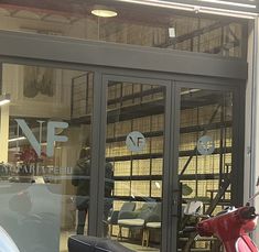 a red scooter parked in front of a building with glass doors and windows