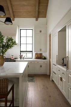 a large kitchen with white cabinets and wood flooring on the walls, along with a wooden ceiling