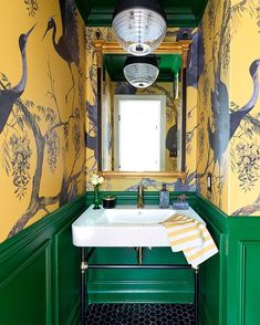 a bathroom with yellow and green wallpaper has a white sink in front of a mirror