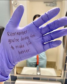 a purple glove with writing on it in front of a bathroom mirror and people sitting at the sink