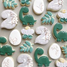 cookies decorated with green and white icing are arranged in the shape of dinosaurs