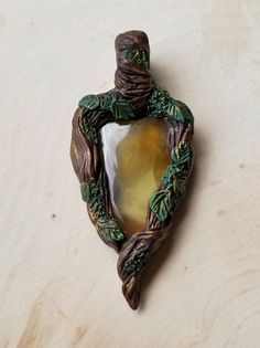 A lovely transparent yellow prehnite crystal portal necklace. Earthy foliage adorn a mossy "tree" branch wrap I sculpted from clay. A soft golden dust lightly accents the design. I made this pendant by hand using a high quality polymer clay designed for durability and wear. There is a metal reinforcement inside of the bail for added strength (the piece that rests on the chain). The rich, glistening color is created with a special pigmentation process I developed using a series of techniques. It is sealed with a non yellowing matte varnish that will protect the pigment for years to come! SIZING: 2.25" x 1" x 0.25" WEIGHT: 0.42oz MATERIALS: Polymer clay Matte varnish Prehnite Your choice of chain. See below + photos DETAILS: Lightweight Durable Chip resistant Non fade Non yellowing Vegan CHA Nature-inspired Carved Jewelry For Healing, Handmade Resin Jewelry Nature-inspired, Handmade Resin Necklaces With Nature-inspired Style, Unique Yellow Polymer Clay Jewelry, Handmade Nature-inspired Polymer Clay Jewelry, Mossy Tree, Clay Design, Tree Branches, Polymer Clay