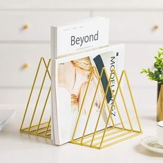 a magazine rack sitting on top of a table next to a cup and saucer