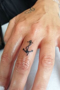 a woman's hand with a small anchor tattoo on her left thumb and finger