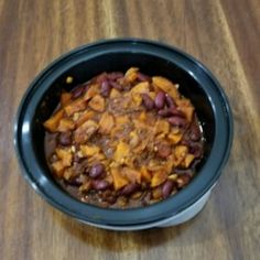 a bowl filled with chili and beans on top of a wooden table