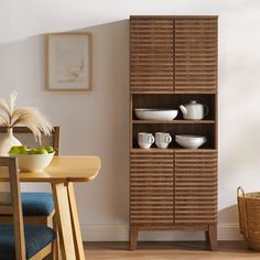 a wooden cabinet sitting next to a table with plates and bowls on top of it