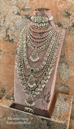 an elaborate necklace and earring set is displayed on a stand in front of a floral wall