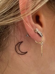 a woman's left ear has a small key tattoo on it