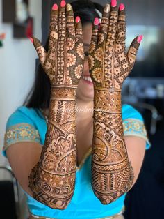 a woman holding her hands up to show the hendi