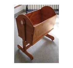 a wooden toy cradle with wheels on the floor