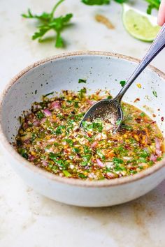 a person is spooning in a bowl filled with food and garnished with cilantro