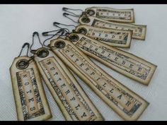 six old fashioned bookmarks with numbers and letters hanging from the strings on a white table