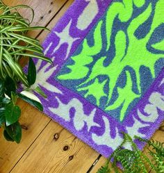 a purple and green rug sitting on top of a wooden floor next to a potted plant