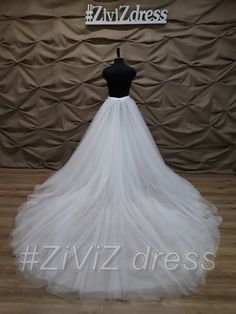 a white wedding dress is displayed on a mannequin headdress in front of a backdrop