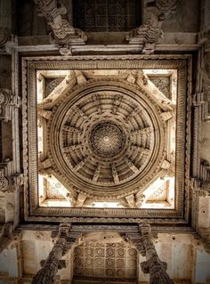 an intricate ceiling in the middle of a building with columns and carvings on it's sides