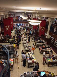 people are browsing through books in a library with red banners hanging from the ceiling