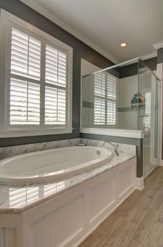 a large white bath tub sitting in a bathroom next to a walk - in shower