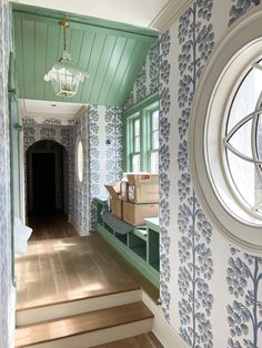 the hallway is decorated with blue and white wallpaper, along with wooden steps leading up to a round window