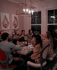 a group of people sitting around a dining room table eating food and drinking wine together