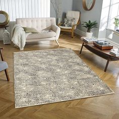 a living room filled with furniture and a rug on top of a hard wood floor