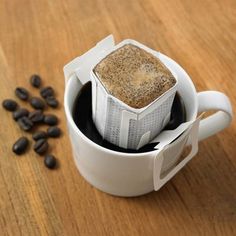 there is a coffee filter in the cup and some beans on the table next to it