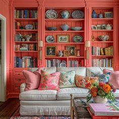 a living room filled with lots of furniture and bookshelves covered in colorful pillows