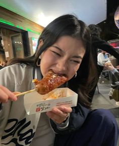 a woman eating food with chopsticks in her mouth