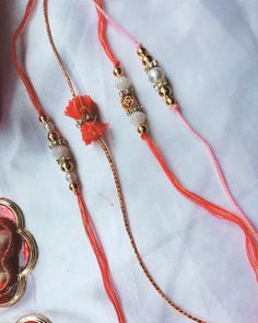 three necklaces with beads and charms on a white table cloth next to a cup