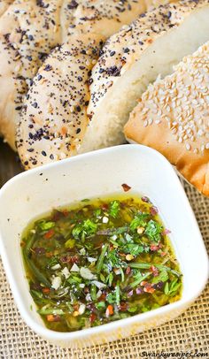 a bowl of soup next to two bagels on a tablecloth with sesame seed sprinkles