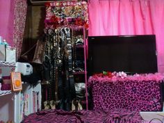 a bedroom with pink curtains and leopard print bedding on the floor, shelving in front of a tv