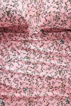 a pink background with small flowers and birds on it's side, as well as the fabric