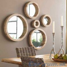 a dining room table with four circular mirrors on the wall and candles in front of it