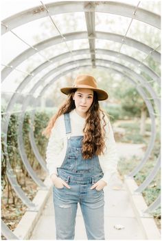 a young woman wearing overalls and a hat