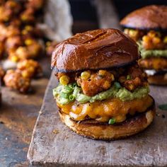 a chicken sandwich with guacamole and corn on it sitting on a cutting board