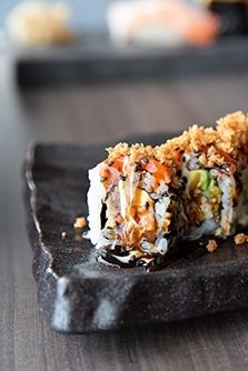 a black plate topped with sushi covered in toppings