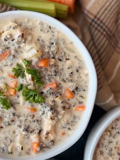 two white bowls filled with soup next to carrots and celery