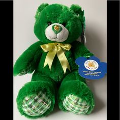 a green teddy bear with a yellow ribbon around its neck