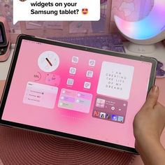 a person holding an ipad in front of a pink background with text that reads, what are the widgets on your samsung tablet?