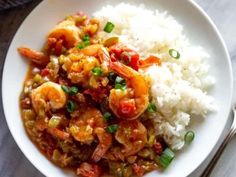 a white bowl filled with rice and shrimp on top of a table next to a fork