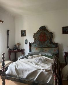 an old fashioned bed in a room with white walls and flooring, along with other antique furniture